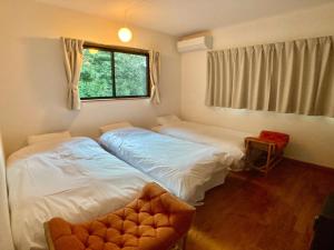 two beds in a room with a window and a chair at ＡＴＴＡ ＨＯＴＥＬ ＫＡＭＡＫＵＲＡ / Vacation STAY 76829 in Kamakura