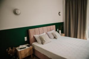 a bedroom with a large bed with a green wall at Sam Las Apartamenty Białowieża in Białowieża