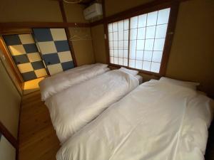 2 letti in una piccola camera con 2 finestre di ＡＴＴＡ ＨＯＴＥＬ ＫＡＭＡＫＵＲＡ / Vacation STAY 77545 a Kamakura