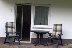 uma mesa e duas cadeiras em frente a uma casa em Appartement, komplett saniert, 47 m², mit Terrasse und Gartennutzung em Meinerzhagen