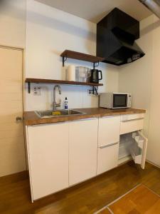 una cucina con armadi bianchi, lavandino e forno a microonde di ＡＴＴＡ ＨＯＴＥＬ ＫＡＭＡＫＵＲＡ / Vacation STAY 77545 a Kamakura