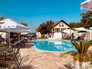 a swimming pool with chairs and umbrellas next to a house at ElGringo Clisura Dunarii in Moldova Nouă