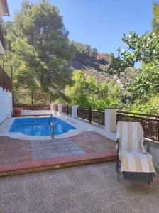 einen Pool mit einem Stuhl neben einem Haus in der Unterkunft El balcón de Cuadros in Bedmar
