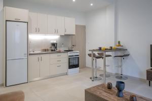 une cuisine avec des placards blancs et une table. dans l'établissement Central appartment, Ierapetra, à Ierápetra