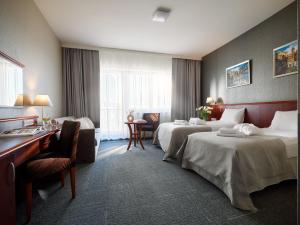 ein Hotelzimmer mit 2 Betten und einem Schreibtisch in der Unterkunft Arka Medical Spa in Kołobrzeg