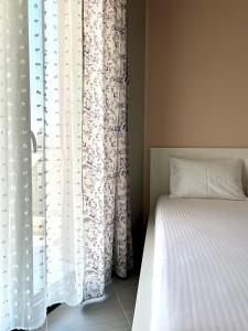 een slaapkamer met een bed en een raam met gordijnen bij SnappyB - Colours in Alexandroupoli