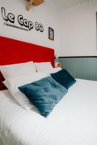 a large white bed with blue pillows on it at Le Cap 80… La suite des nostalgiques in Gujan-Mestras