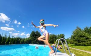 a young girl jumping into a swimming pool at Bieszczadzki Ośrodek Wypoczynkowo Konferencyjny DANFARM in Ustrzyki Dolne
