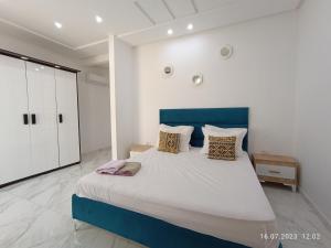 a bedroom with a large bed with a blue headboard at Residence Debbabi in Monastir