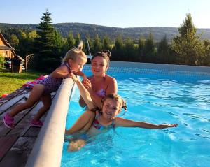 un grupo de tres chicas sentadas en el borde de una piscina en Bieszczadzki Ośrodek Wypoczynkowo Konferencyjny DANFARM, en Ustrzyki Dolne