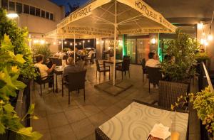 AZUL Hotel & Restaurant Partizánske في بارتيزانسكى: مطعم فيه ناس جالسين على الطاولات تحت مظله