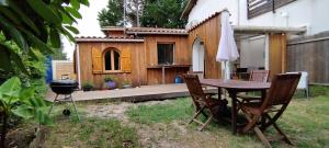 een achtertuin met een tafel en stoelen en een grill bij A la petite maison in Arès