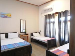 Zimmer mit 2 Betten und einem Spiegel in der Unterkunft Aiden Homestay in Pasikuda