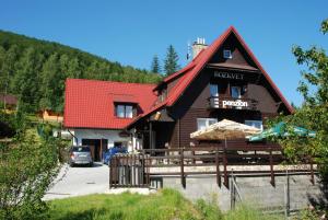 a large wooden building with a red roof at Penzion Rozkvet in Frenštát pod Radhoštěm