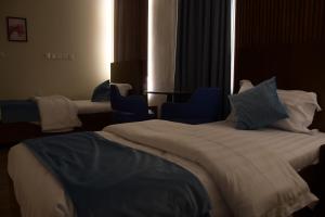 een hotelkamer met 2 bedden en 2 blauwe stoelen bij فندق ايلاف الشرقية 2 Elaf Eastern Hotel 2 in Sayhāt