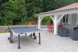a ping pong table on a patio with a gazebo at Au bois dormant in Pont-du-Casse