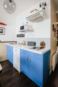 a kitchen with blue cabinets and a white counter top at Le Cap 80… La suite des nostalgiques in Gujan-Mestras