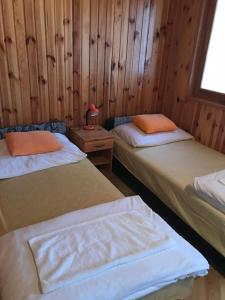 two beds in a room with wooden walls at Cuki lak in Kiszombor