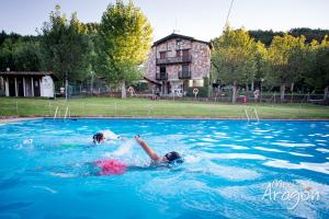 two people in the water in a swimming pool at Bungalows Baliera in Bonansa