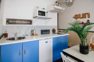 a kitchen with blue cabinets and a sink at Le Cap 80… La suite des nostalgiques in Gujan-Mestras