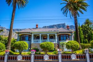 ケープタウンにあるCape Riviera Guesthouseのヤシの木と山を背景にした家