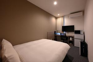 佐賀市にあるHOTEL R9 The Yard 江北のベッド、デスク、コンピュータが備わるホテルルームです。