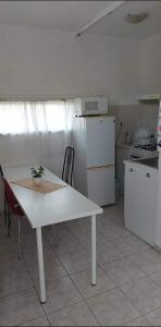 eine Küche mit einem weißen Tisch und einem weißen Kühlschrank in der Unterkunft Badacsonyi privát bérlemény in Badacsonytomaj