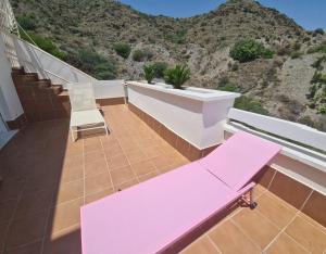 un banco rosa en un balcón con una montaña en TRIPLEX DE LUJO EN MOJACAR en Mojácar