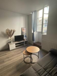 a living room with a table and a couch at Appartement calme au cœur de la ville in Lons-le-Saunier