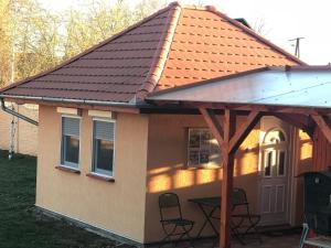a small house with an orange roof and chairs at Cuki lak in Kiszombor