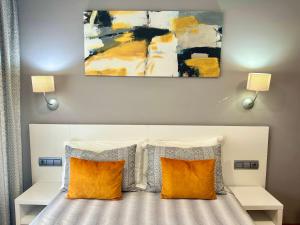 a bedroom with a bed with two pillows and a painting at Hotel Las Olas in Noja