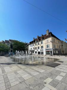 a fountain in the middle of a square with buildings at Appartement calme au cœur de la ville in Lons-le-Saunier