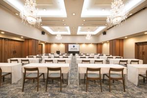 a conference room with tables and chairs and chandeliers at HOTEL MYSTAYS Kumamoto Riverside in Kumamoto