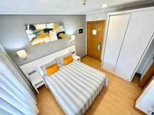 1 dormitorio con cama blanca y almohadas de color naranja en Hotel Las Olas, en Noja