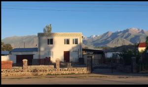 a white house with a fence and mountains in the background at MALIKA Guest House in Kochkorka