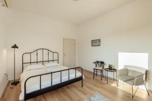 a white bedroom with a bed and a chair at City port Apartment in Herceg-Novi