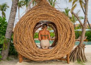 a woman sitting in a large wicker chair on the beach at Sensations Eco-Chic Hotel in Pwani Mchangani Mdogo