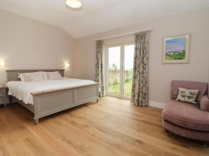 um quarto com uma cama, uma janela e uma cadeira em Cotswold View em Chipping Norton