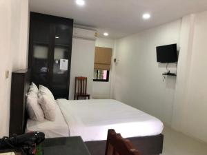 a bedroom with a white bed and a tv at พิชชาวรี รีสอร์ท in Ban Si Thep (2)