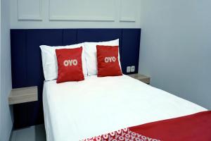 a bed with two red pillows on top of it at Capital O 92804 La Tansa Syariah Hotel in Cibeber