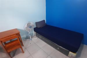 a room with a bed and a fan and a table at SPOT ON 92814 Gioba Kost Syariah in Grobogan