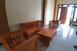 two wooden benches in a room with a door at OYO Life 92812 Galih Kostel 2 Syariah in Grobogan