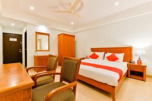 a bedroom with a bed and a desk and a table at Vembanad Tourist Home in Vaikom