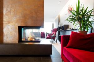 a living room with a fireplace and a red couch at Bio- und Wellnesshotel Alpenblick in Höchenschwand