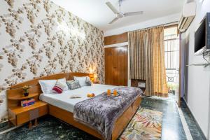 um quarto com uma cama e uma televisão em Homlee-3bhk Green Luxury in SDEL em Nova Deli