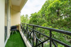 uma varanda com uma cadeira e relva verde em Homlee-3bhk Green Luxury in SDEL em Nova Deli