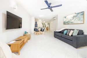 Cairns Esplanade 2BR Waterfront Apartment Sleeps 6 في كيرنز: غرفة معيشة مع أريكة وتلفزيون بشاشة مسطحة