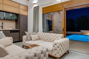uma sala de estar com mobiliário branco e uma piscina em Unique Villa Pietra with heated private pool em Šestanovac