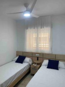 una camera da letto con due letti e una finestra di Apartamento con vistas al mar y montaña a Oropesa del Mar Altre 15 foto