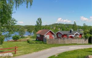 a red house with a fence next to a lake at Gorgeous Home In Boxholm With House Sea View in Boxholm
